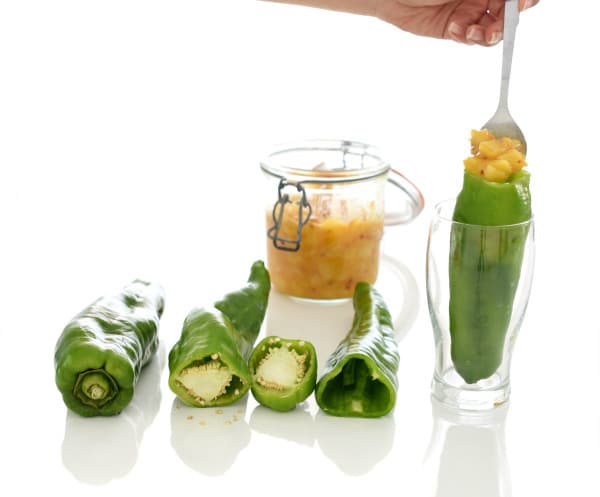 Vacía los pimientos de semillas y colócalos dentro de un vaso para rellenarlos fácilmente